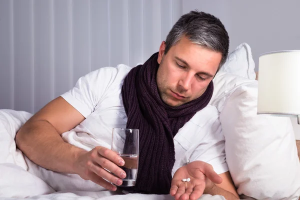 Kranker schaut sich Pillen an — Stockfoto