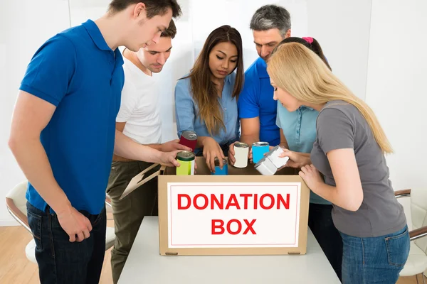 Personas mirando dentro de la caja de donación — Foto de Stock