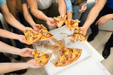 Pizza dilimleri tutan insanlar