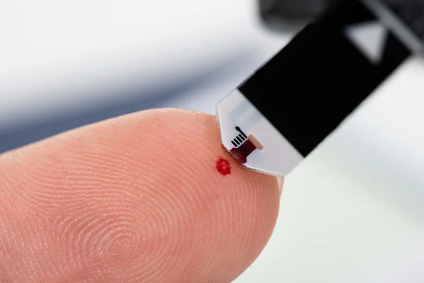 Палець людини з глюкометром — стокове фото