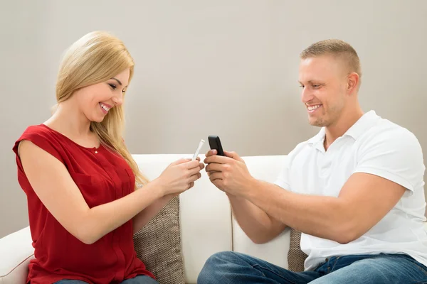 Casal conversando com telefones celulares — Fotografia de Stock