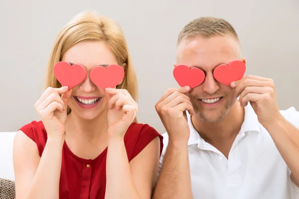 Casal cobrindo os olhos com corações — Fotografia de Stock