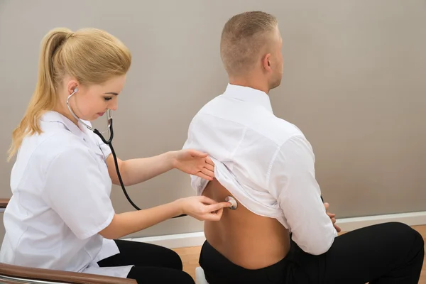 Médico examina la espalda del paciente — Foto de Stock