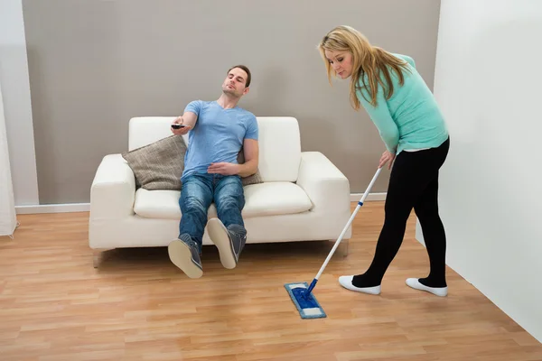 Woman Cleaning Floor While Man On Sofa — Stock Photo, Image