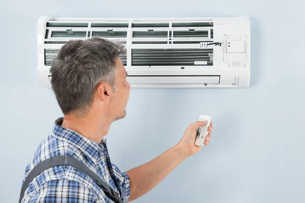 Reparatör verksamma luftkonditionering med fjärrkontroll — Stockfoto