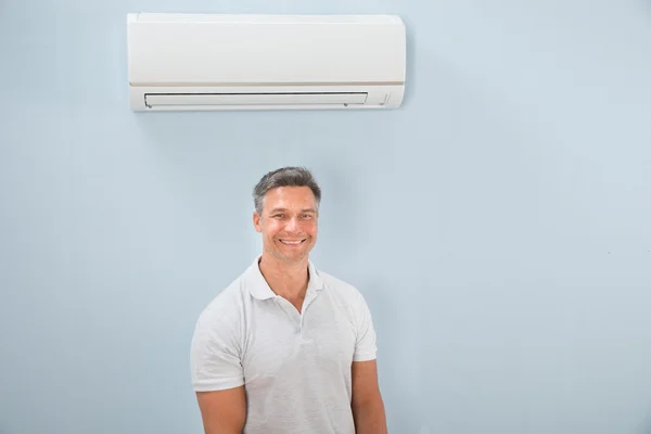 Muž, který stojí za klimatizaci — Stock fotografie