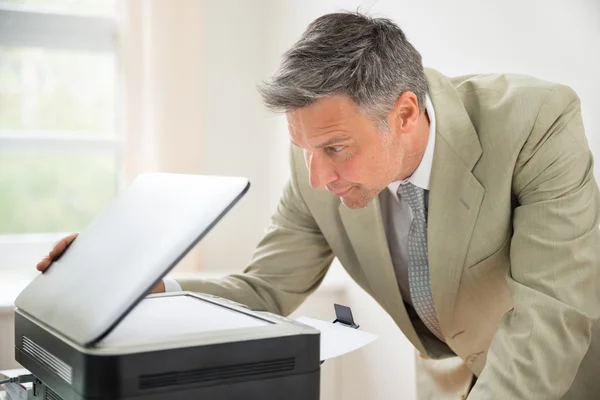 Empresário olhando para a máquina de fotocópia — Fotografia de Stock