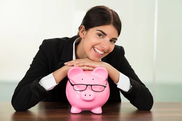 Mujer de negocios con Piggybank en el escritorio — Foto de Stock