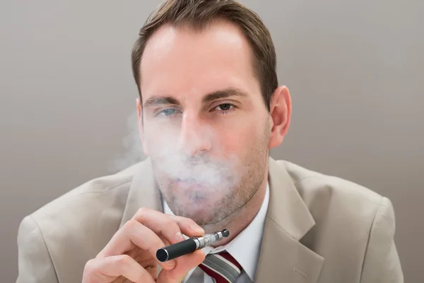 Бизнесмен курит электронную сигарету — стоковое фото
