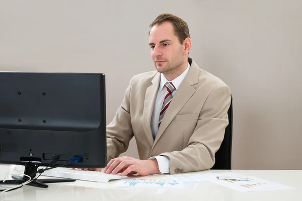 Geschäftsmann mit Computer und Grafiken — Stockfoto