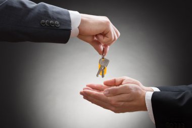 Businessman's Hand Giving House Key clipart