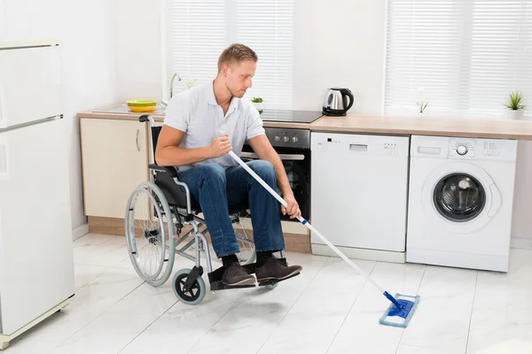 在清洁地板的轮椅上的男人 — 图库照片