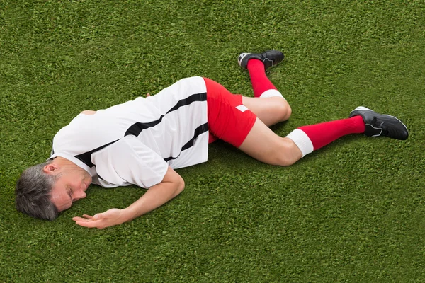 Jugador de fútbol acostado en la hierba — Foto de Stock