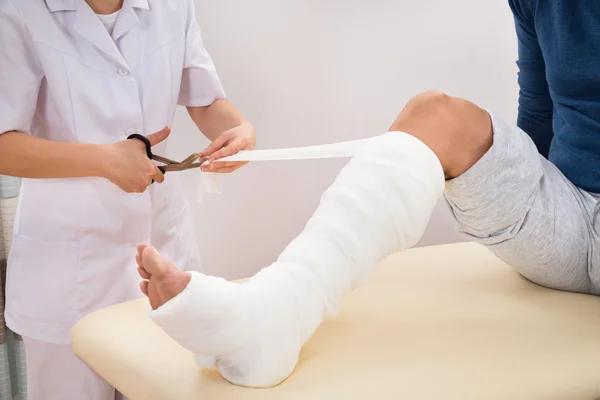 Lekarz Bandaging pacjenta nogi — Zdjęcie stockowe