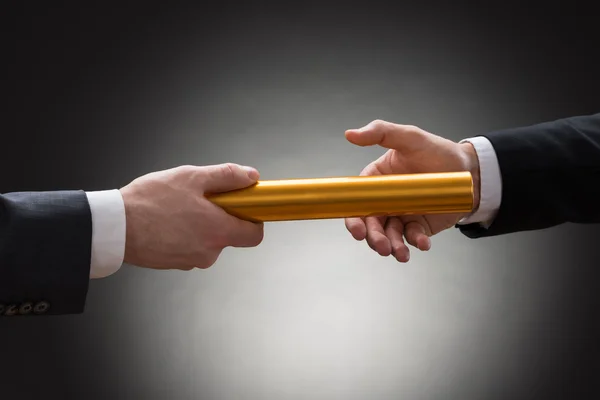 Mãos passando Baton relé dourado — Fotografia de Stock