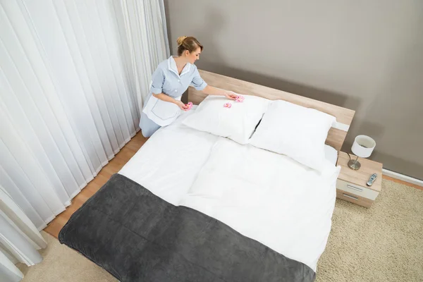 Pokojówka dekorowanie sypialni z płatkami — Zdjęcie stockowe