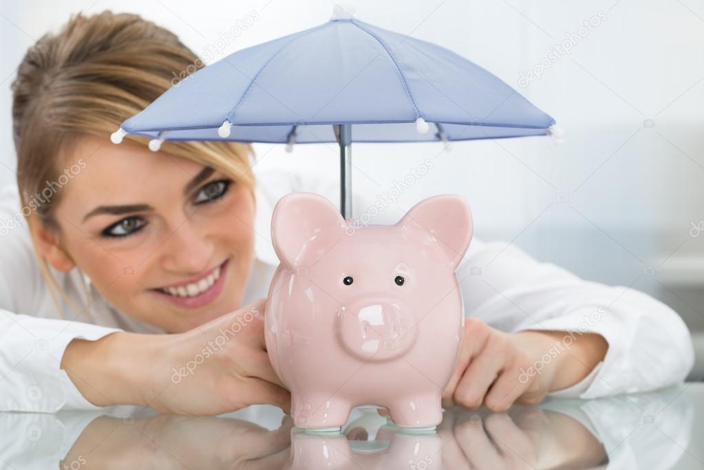 Businesswoman Sheltering Piggybank