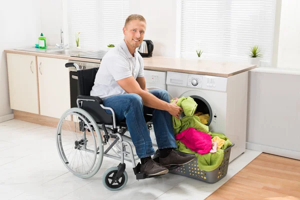 Uomo su sedia a rotelle con lavatrice — Foto Stock