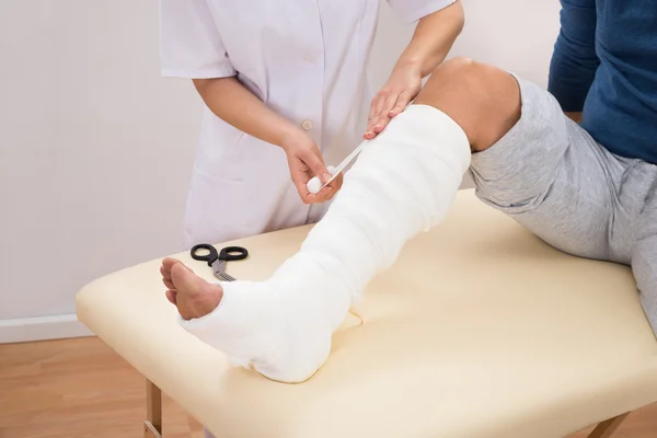Médecin bandage jambe de patient — Photo