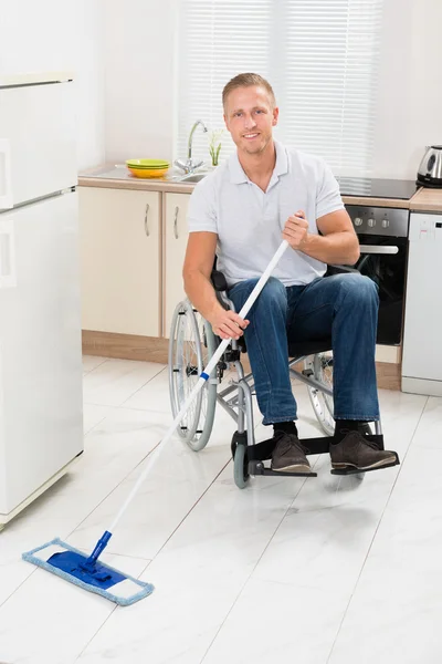 Ανάπηρο άνθρωπο σε αναπηρικό καροτσάκι καθαρίζοντας πάτωμα — Φωτογραφία Αρχείου
