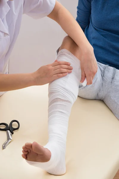 Läkare bandage patientens ben — Stockfoto