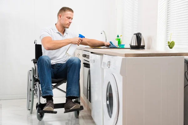 Man op rolstoel schoonmaken inductie kookplaat — Stockfoto