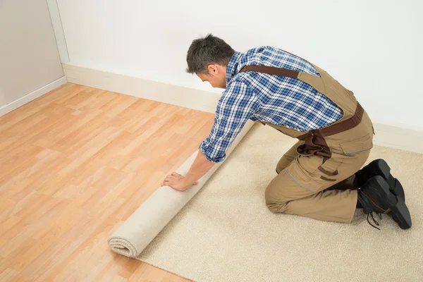 Arbeiter rollt Teppich auf Fußboden aus — Stockfoto