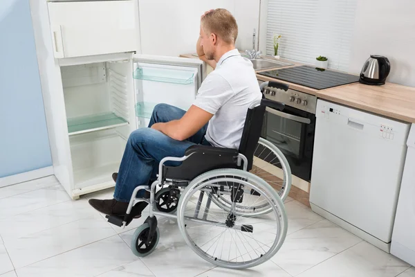 Hombre discapacitado mira en el refrigerador — Foto de Stock