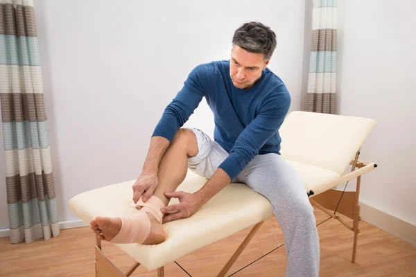 Homme attachant bandage à son pied — Photo