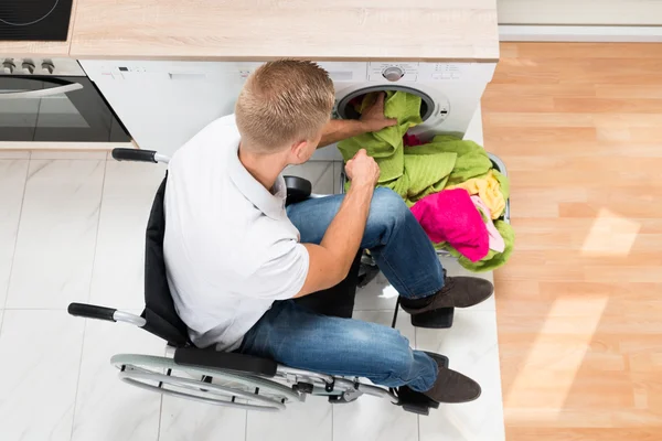 Άνθρωπος στην αναπηρική καρέκλα, βάζοντας πλυντήριο — Φωτογραφία Αρχείου