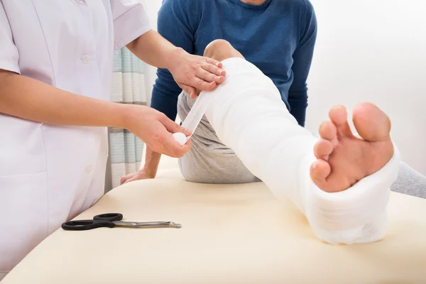 Doctor Bandaging Patient's Leg — Stock Photo, Image