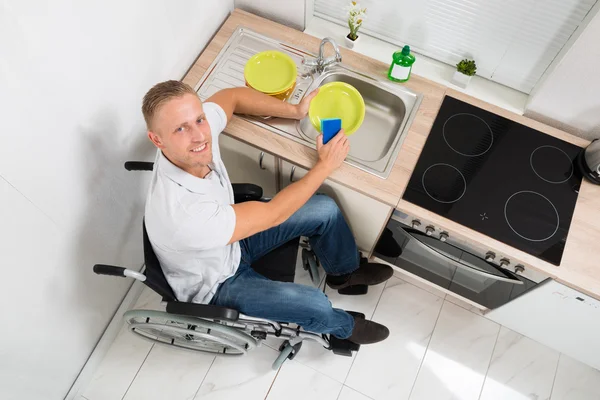 Hombre en silla de ruedas Platos de lavado — Foto de Stock