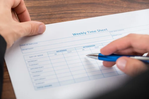 Person Hand Filling Weekly Time Sheet