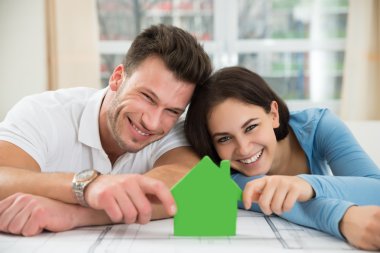 Yeşil ev modeli tutan Çift