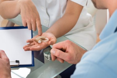 Genç doktor gösteren işitme cihazı