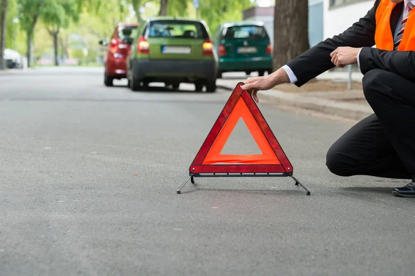 Hombre colocando triángulo de advertencia —  Fotos de Stock