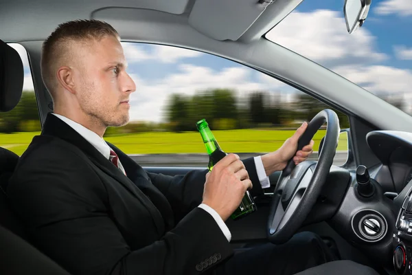 Geschäftsmann trinkt Bier im Auto — Stockfoto