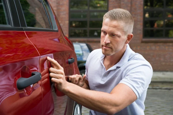 Junger Mann sucht Kratzer am Auto — Stockfoto