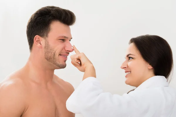 Mujer aplicando humectante en nariz de hombre —  Fotos de Stock