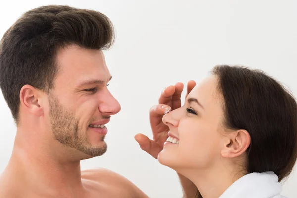 Hombre aplicando humectante en la nariz de la mujer —  Fotos de Stock