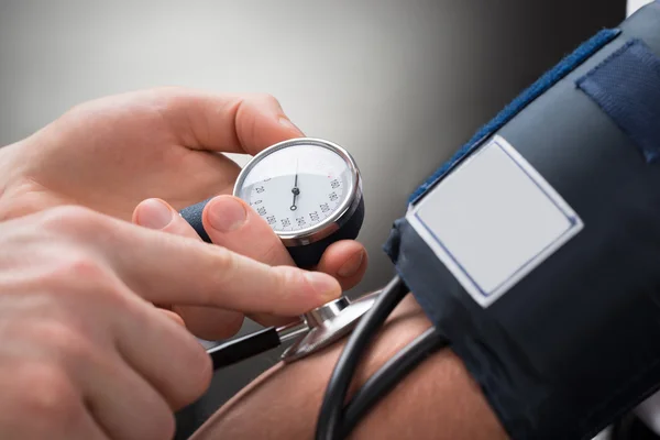 Médico mão verificando a pressão arterial — Fotografia de Stock