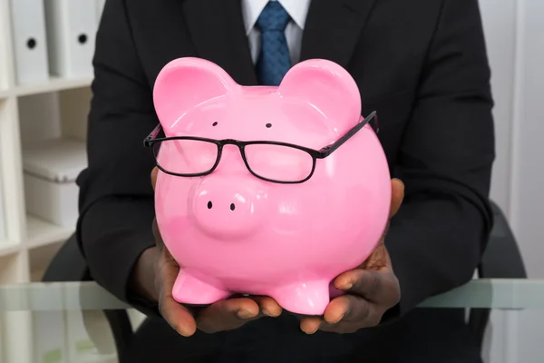 Homem de negócios segurando piggybank — Fotografia de Stock