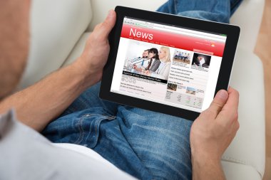 Kişi dijital tablet haberleri izlerken kanepede Close-Up