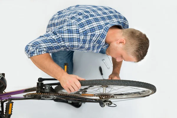 Homem que fixa roda de bicicleta — Fotografia de Stock