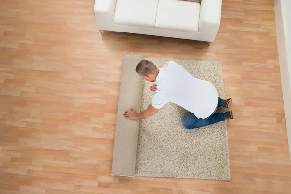 Mann rollt Teppich aus — Stockfoto