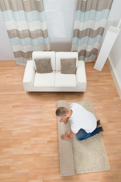 Hombre desenrollando alfombra — Foto de Stock