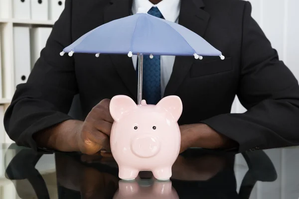 Zakenman met spaarpot en parasol — Stockfoto