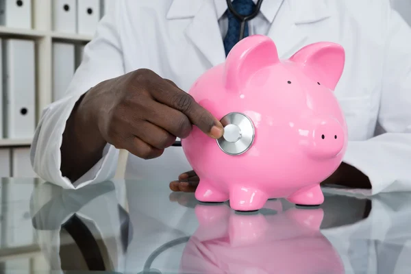 Doctor Examining Piggybank — Stock Photo, Image