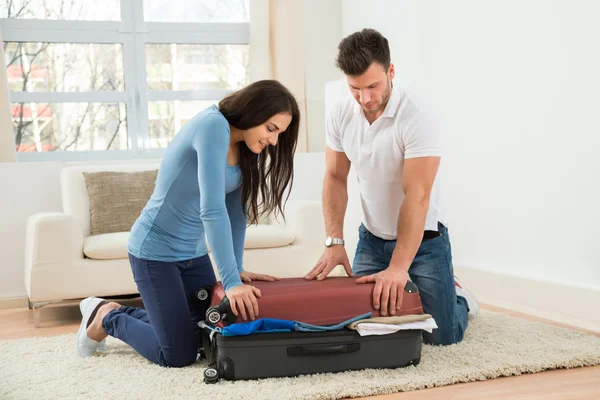 Couple Trying To Close Suitcase