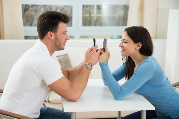 Lyckliga par textning på mobiltelefoner — Stockfoto